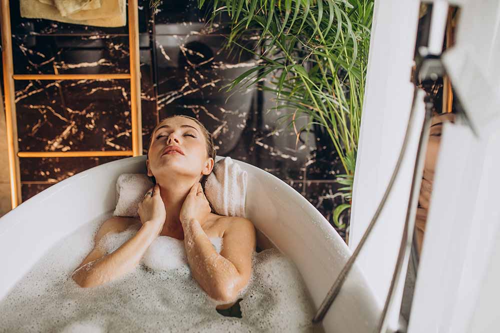 Krásná mladá žena relaxuje ve vaně plné bublinek